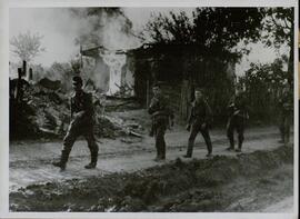 Grupo de soldados caminando a través de un poblado ruso ardiendo. Fotografía de prensa de la agencia de Heinrich Hoffmann.