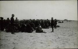 Refugiados republicanos españoles esperan sobre la arena  del Campo de concentración de Argelés en Canet Plage (Pyrenees Orientales), 1939.  Perteneciente a un conjunto de fotografías de la llegada de refugiados españoles republicanos al Campo de concentración de Argelés al finalizar la Guerra Civil española, 1939.